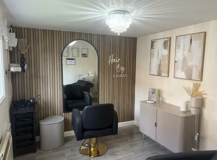The salon: walnut slat wall with the neon Hair by Lauren sign, arched mirror and a black chair on a gold base